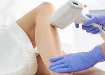 A medical professional uses a skincare device on a woman's leg during a treatment session to promote long-term skin health.