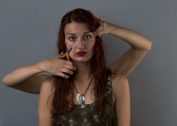 Woman with facial markings and extra arms holding scissors, symbolising inner conflict and distorted self-image linked to body dysmorphic disorder.