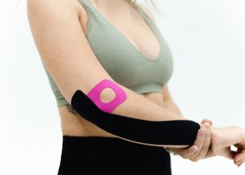 Woman wearing kinesiology tape on a healing broken arm
