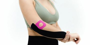 Woman wearing kinesiology tape on a healing broken arm
