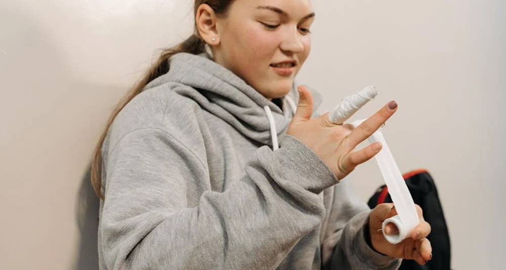 Young woman wrapping tape around a broken finger