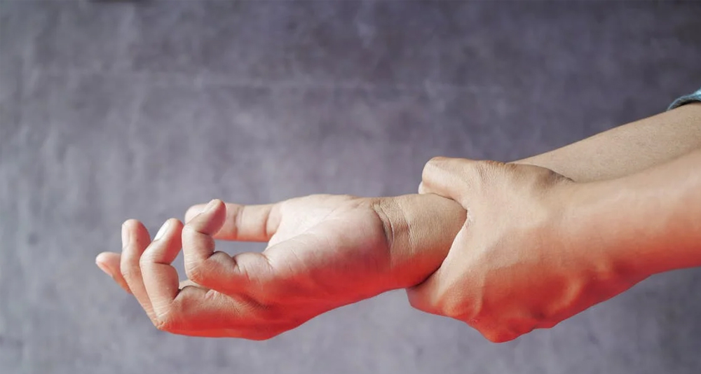 Person holding their injured wrist in pain