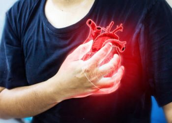 Person clutching chest with digital heart overlay indicating cardiac distress