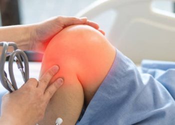 Doctor examining a patient's swollen knee with visible inflammation
