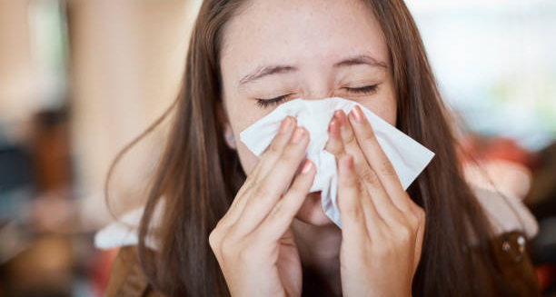Woman sneezing into a tissue due to catarrh symptoms