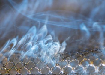 Smoke rising from a metallic mesh surface, illustrating carbon monoxide emission