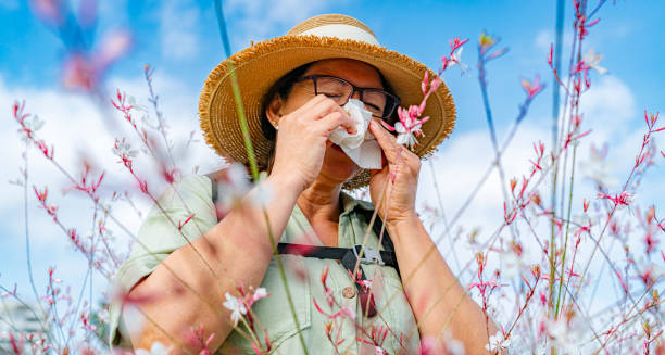 Woman sneezing in a field of flowers due to seasonal allergies
