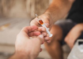 Close-up of two people exchanging a syringe filled with liquid