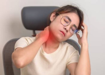 Woman experiencing neck pain, touching the back of her neck