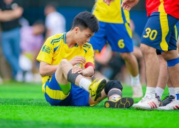 Injured football player sitting on field holding his leg