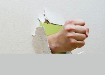 Fist punching through drywall, symbolising trauma to the hand or thumb