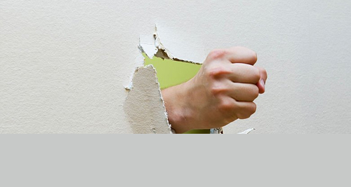 Fist punching through drywall, symbolising trauma to the hand or thumb