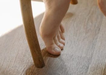 Barefoot toe hitting wooden chair leg on hard floor