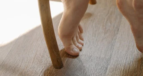 Barefoot toe hitting wooden chair leg on hard floor