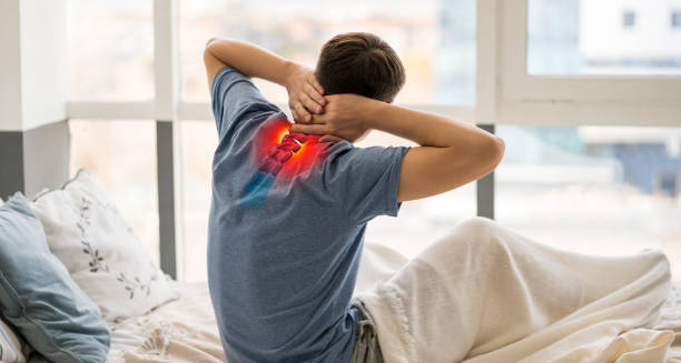 Man sitting on bed holding neck with highlighted spine pain
