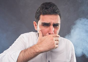 Man coughing and surrounded by smoke, indicating carbon monoxide exposure