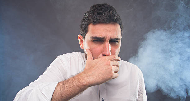 Man coughing and surrounded by smoke, indicating carbon monoxide exposure
