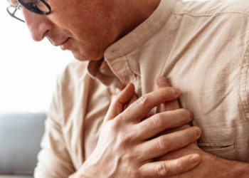 Man clutching his chest in discomfort, possibly due to cardiomyopathy