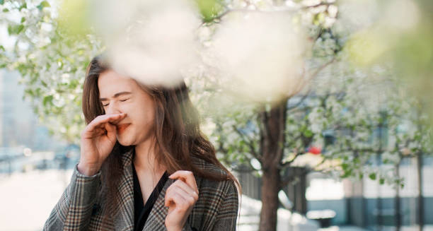 Woman sneezing outdoors during allergy season
