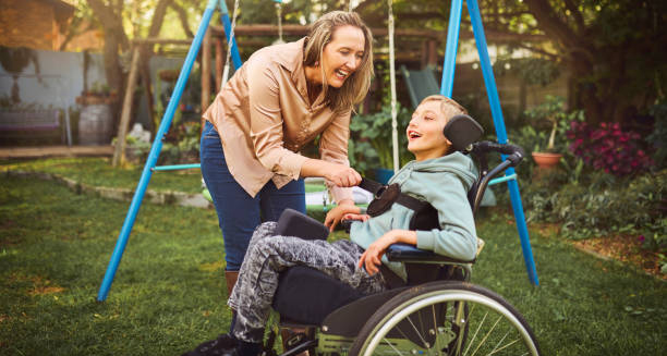 Child in a wheelchair smiling with caregiver in a sunny park
