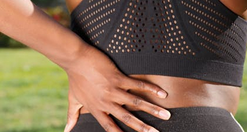 Person holding lower back in pain during outdoor activity