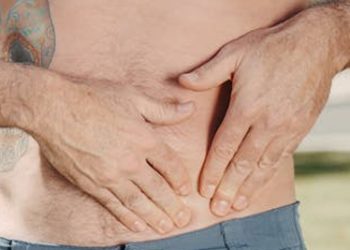 Man pressing on his pelvic area, indicating discomfort or injury