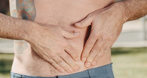Man pressing on his pelvic area, indicating discomfort or injury