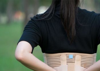 Woman wearing a rib brace to support recovery from a fractured rib outdoors