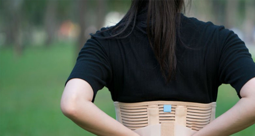 Woman wearing a rib brace to support recovery from a fractured rib outdoors