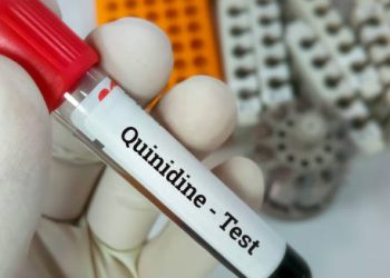 Gloved hand holding a blood sample tube labelled Quinidine Test