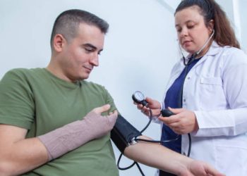 Nurse checking blood pressure of patient with bandaged arm