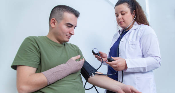 Nurse checking blood pressure of patient with bandaged arm