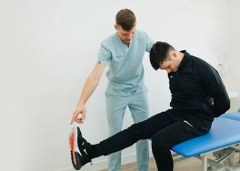 Physiotherapist assessing a patient's leg movement during examination