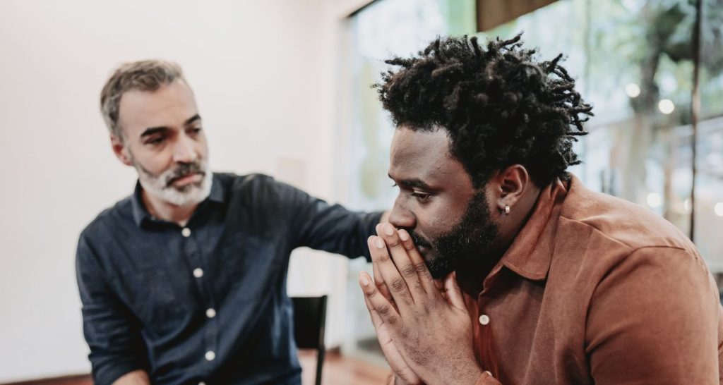 Man offering emotional support to a distressed individual during a panic attack