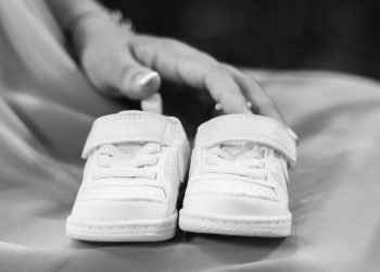Small white baby shoes on a person's lap