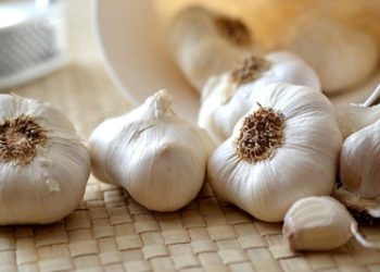 Fresh garlic bulbs spilled on a woven mat, symbolising natural anti-inflammatory remedies for chronic conditions like Behçet’s disease.