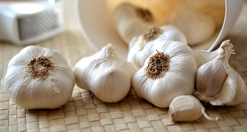 Fresh garlic bulbs spilled on a woven mat, symbolising natural anti-inflammatory remedies for chronic conditions like Behçet’s disease.