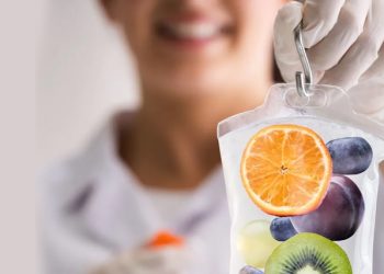 Smiling healthcare provider holding IV bag filled with images of fruits, symbolising nutritional therapy for bile duct cancer support.