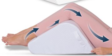 Legs elevated on a wedge cushion to reduce swelling and manage symptoms of Baker’s cyst behind the knee.