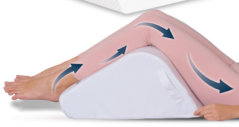 Legs elevated on a wedge cushion to reduce swelling and manage symptoms of Baker’s cyst behind the knee.