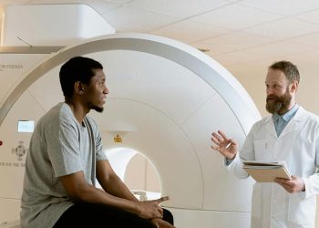 Doctor discussing brain scan results with patient near MRI machine