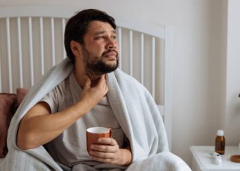 Man experiencing sore throat and fatigue, early symptoms of bronchitis