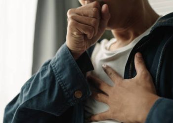 Person coughing and holding chest, indicating discomfort