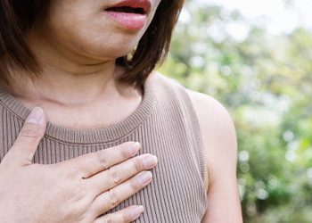 Woman clutching chest due to shortness of breath, a symptom of cardiomyopathy