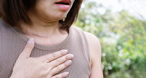 Woman clutching chest due to shortness of breath, a symptom of cardiomyopathy