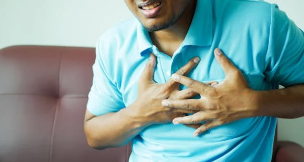 Man clutching chest in pain, showing signs of cardiovascular distress
