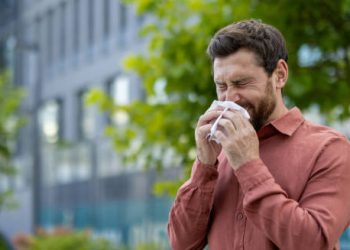 Man sneezing outdoors due to nasal congestion