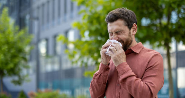 Man sneezing outdoors due to nasal congestion