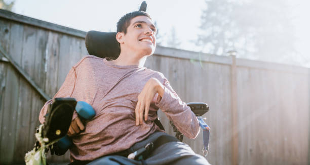 Young man in a motorised wheelchair smiling outdoors