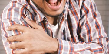 Man holding arm in pain, indicating symptoms of a broken arm